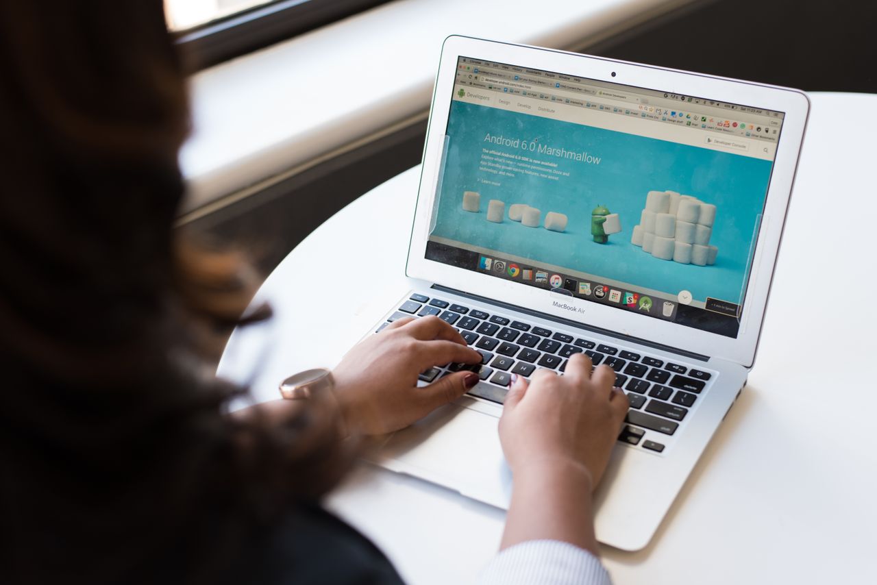 digital Businesswoman working on laptop with Android 6.0 Marshmallow webpage open.